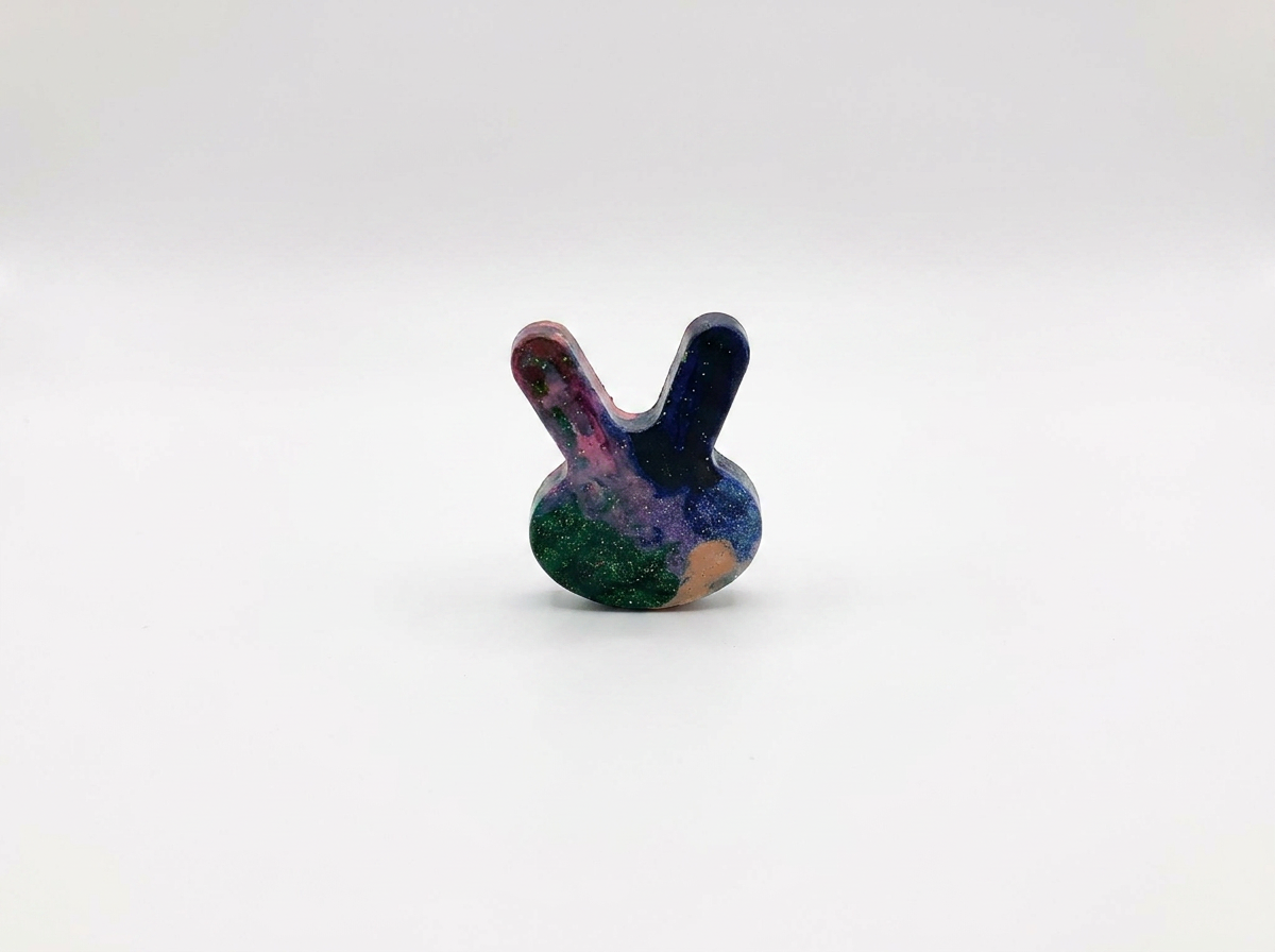 Handmade bunny-shaped Waxadoodle crayon in dark blue, green and pink with glitter
