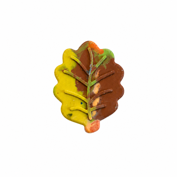 A swirly fall leaf-shaped crayon in yellow, brown, and green on a pure white background